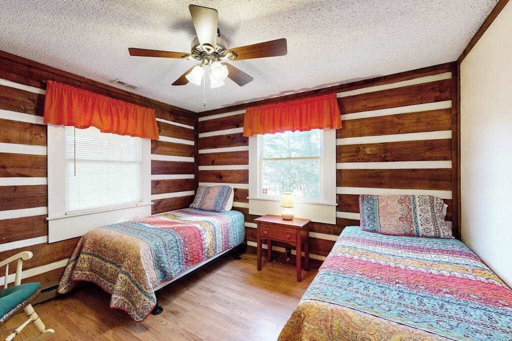 Eine Hütte mit zwei Betten, einem Deckenventilator und Holzwänden.