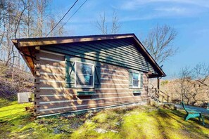 Eine Blockhütte mit steilem Dach, einer Veranda und einem kleinen Fenster.
