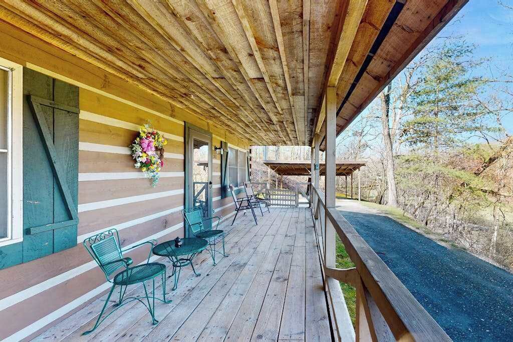 Une véranda couverte avec des poutres en bois, une balustrade et une vue sur la route.