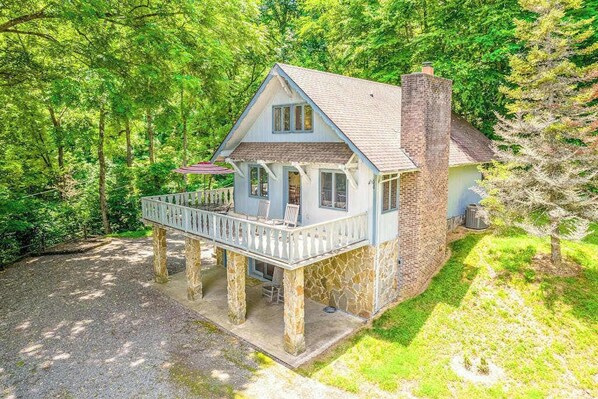 A two-story house with a stone foundation, a brick chimney, and a porch with chairs. - Beautiful home with hot tub, firepit, deck, & central AC (Whittier)