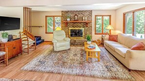 Una sala de estar con chimenea, un sofá, un sillón, una mesa de centro y un televisor.