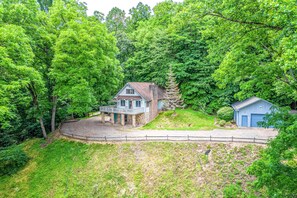 A house surrounded by dense green trees, with a stone porch and a small blue garage. - Beautiful home with hot tub, firepit, deck, & central AC (Whittier)