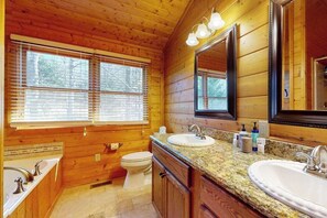 Een houten badkamer in een cabin met twee wastafels, een toilet en een grote spiegel.