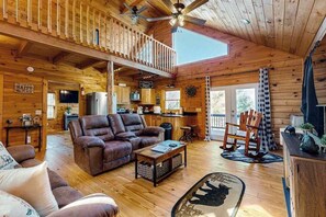 A wooden cabin interior with a living room, kitchen, and a balcony. - Lost Indian Hideaway (Whittier)