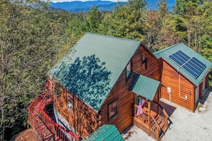 A cabin with a green roof, solar panels, and a red staircase. - Lost Indian Hideaway (Whittier)