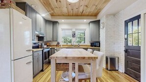 Una cocina moderna con techo de madera, paredes de ladrillo blanco y un ventanal grande.