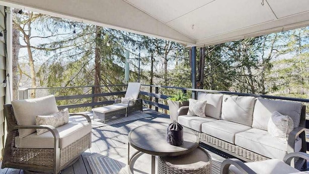 Un espacio al aire libre con techo, amueblado con sillas de mimbre y una mesa redonda, con vista a un paisaje natural.