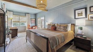 Un dormitorio con una cama grande, una mesita de noche, una lámpara y una ventana.