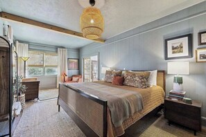 A bedroom with a large bed, a bedside table, a lamp, and a window. - Huckleberry Hill (Waynesville)