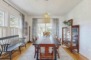 A dining room with a long table, chairs, a bench, a hanging light fixture, and a cabinet with glass doors. - Huckleberry Hill (Waynesville)