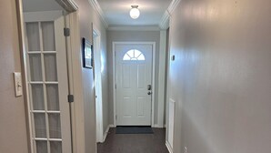 A hallway with a white door, a glass door, and a ceiling light. - Appomattox Family House (College Station)