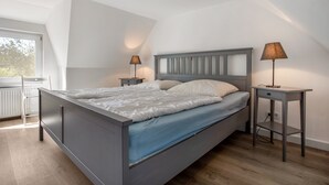 Ein modernes Schlafzimmer mit einem Bett, zwei Nachttischen und einem Fenster.