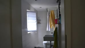 A bathroom with a toilet, sink, and window with blinds.