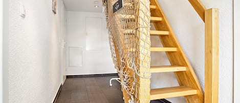 A wooden staircase with a netted barrier, a white door, and a textured wall.