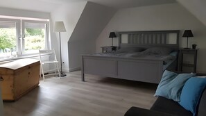 A bedroom with a bed, bedside tables, a desk, a chair, and a window.