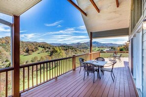 Eine überdachte Terrasse mit Tisch und Stühlen, mit Blick auf eine schöne Landschaft.