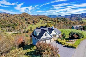 Ein Haus mit geneigtem Dach, umgeben von einem gepflegten Rasen und Bäumen.