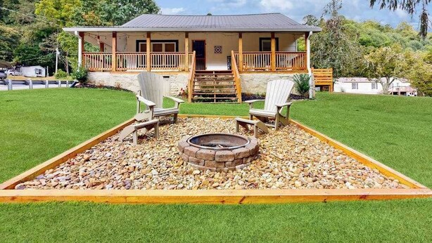 Ein Haus mit Veranda, Feuerstelle und zwei Liegestühlen.