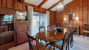 Una habitación con paneles de madera, una gran mesa de comedor de madera, sillas, un aparador y una araña.