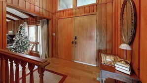 Habitación con paneles de madera, un árbol de Navidad, un espejo y una lámpara sobre una mesa.