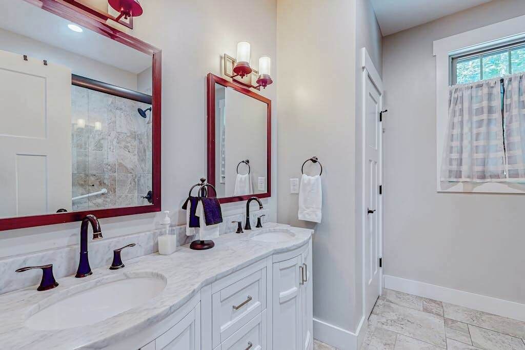 A bathroom with two sinks, a large mirror, and a shower.