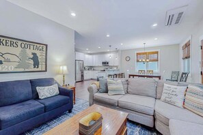 Ein modernes Wohnzimmer mit einer Couch, einem Couchtisch und einer Küche im Hintergrund.