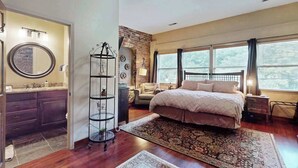 Un dormitorio con cama, lámpara de pie, pared de ladrillo y ventana.