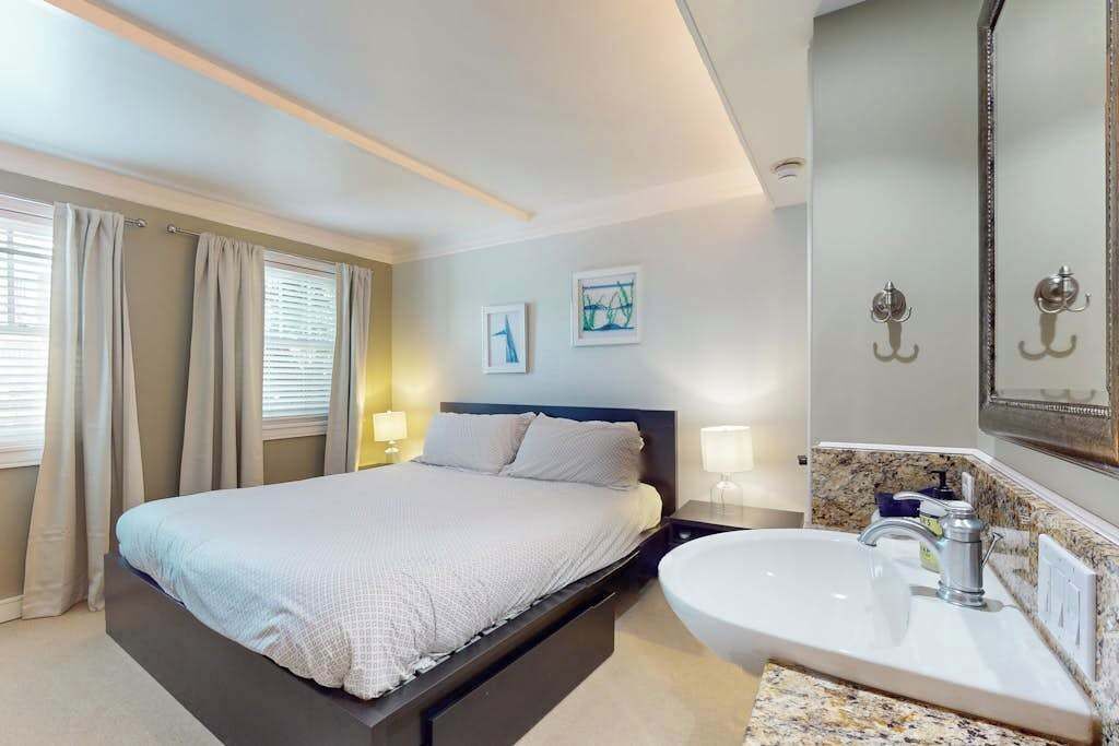 A hotel room with a bed, a bathroom with a sink, and a mirror.