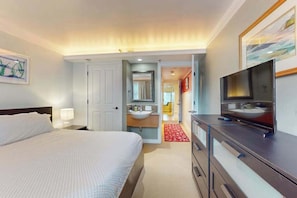 Ein Hotelzimmer mit Bett, Fernseher und einem Badezimmer mit Waschbecken, sowie einem roten Teppich.
