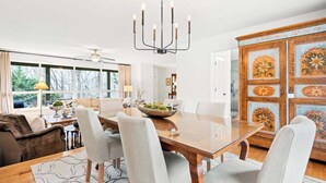 Un comedor con una mesa de madera, seis sillas, una araña y un aparador decorado con motivos florales.