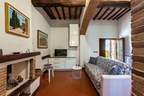 A compact living space with a sofa, a TV, a small table, and a fireplace.