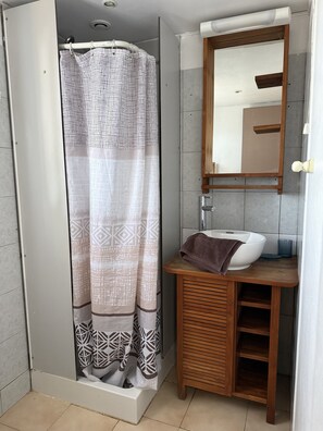 A bathroom with a shower curtain, a sink, and a mirror.