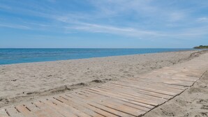 A beach with a wooden walkway leading to the water.