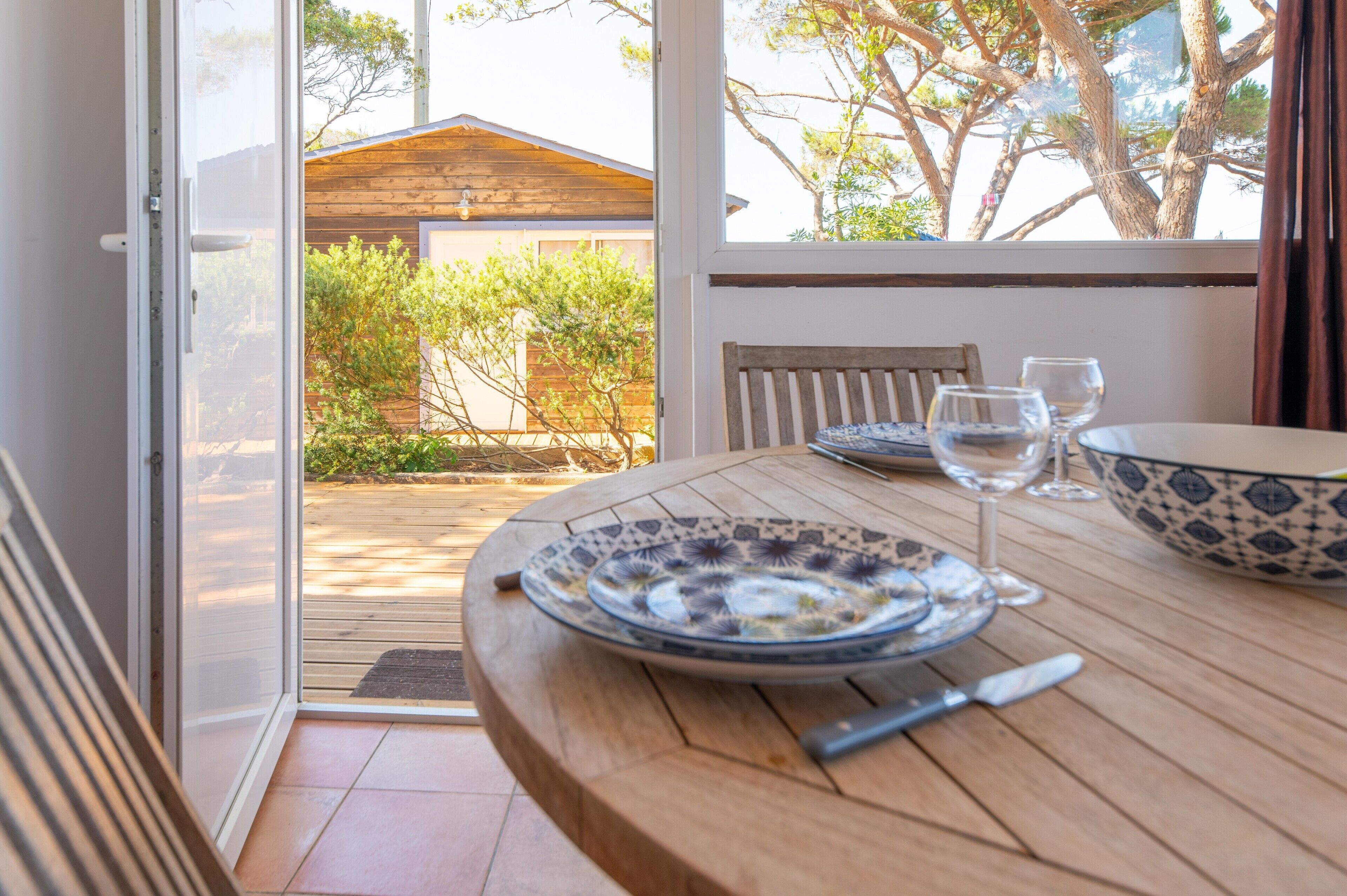 Un coin repas avec une table dressée pour deux personnes, un saladier et des verres à vin.