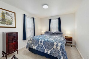 Une chambre à coucher comprenant un lit, une commode, une table de chevet et une lampe fixée au mur.