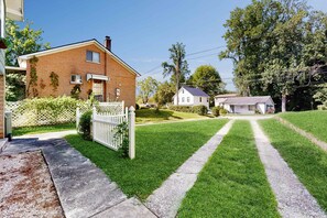 Un quartier résidentiel avec une maison en briques, une clôture blanche et une pelouse bien entretenue.