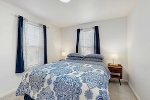 Un dormitorio con una cama, dos mesitas de noche y cortinas.