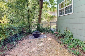 Un jardin avec un foyer extérieur, une terrasse en bois et une serre.