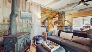 A cozy cabin interior with a stone fireplace, a sofa, and a ceiling fan. - Scenic cabins with fireplaces, children's items, W/D - dog-friendly (Horse Shoe)