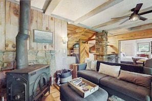 Ein gemütliches Cabin-Interieur mit Kamin, Sofa und Deckenventilator.