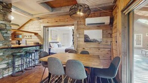 A wooden interior with a dining table, bar stools, and a hanging light fixture. - Scenic cabins with fireplaces, children's items, W/D - dog-friendly (Horse Shoe)