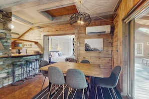 Ein Holzinterieur mit Esstisch, Barhocker und einer Hängeleuchte.