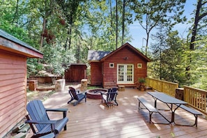 Eine Holzhütte mit Terrasse, Sitzgelegenheiten im Freien und einem Feuerkorb.