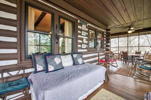 Ein Schlafzimmer einer Blockhütte mit Bett, Stühlen und Tisch.