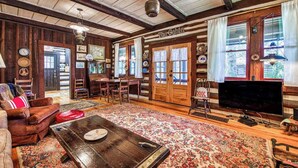 Ein rustikales Ferienhaus-Interieur mit Holzwänden, einem Essbereich, einem Fernseher und einem Kamin.