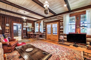 Ein rustikales Ferienhaus-Interieur mit Holzwänden, einem Essbereich, einem Fernseher und einem Kamin.