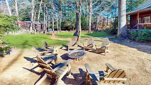 A wooden deck with Adirondack chairs, a fire pit, and a cabin in the background. - Spacious Black Mountain cabin with game room, wood fireplace, firepit, & W/D (Black Mountain)