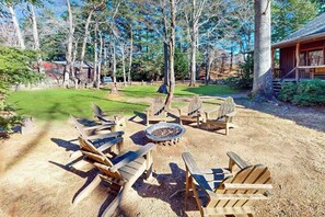 A wooden deck with Adirondack chairs and a fire pit.