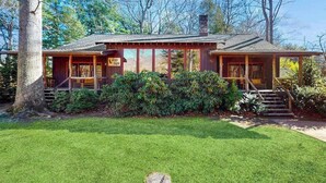 A rustic cabin with a porch, a chimney, and a well-maintained lawn. - Spacious Black Mountain cabin with game room, wood fireplace, firepit, & W/D (Black Mountain)
