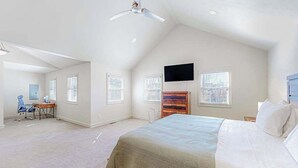 Une chambre à coucher comprenant un lit, un bureau, une chaise, un téléviseur et un ventilateur de plafond.